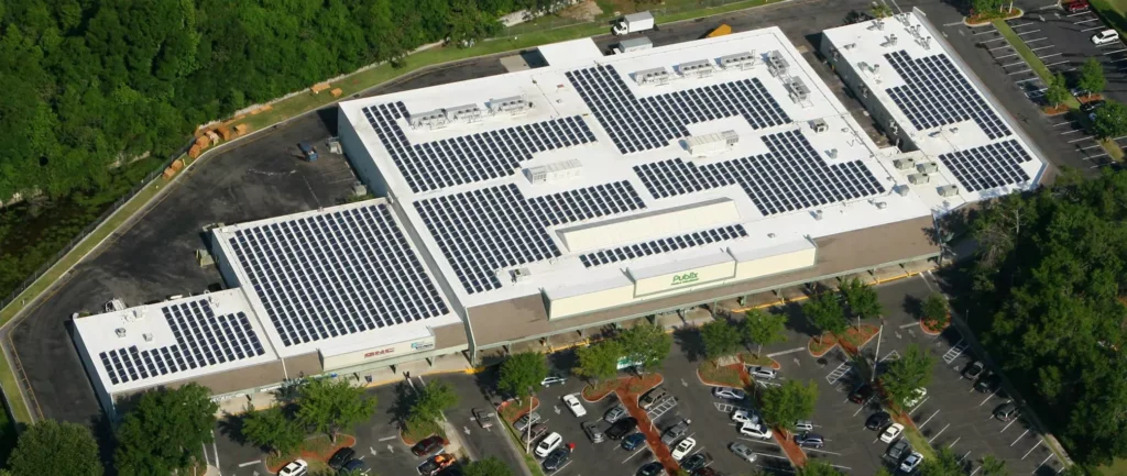 Aerial view of a Publix grocery store with a large solar panel array covering the roof and a parking lot in front.