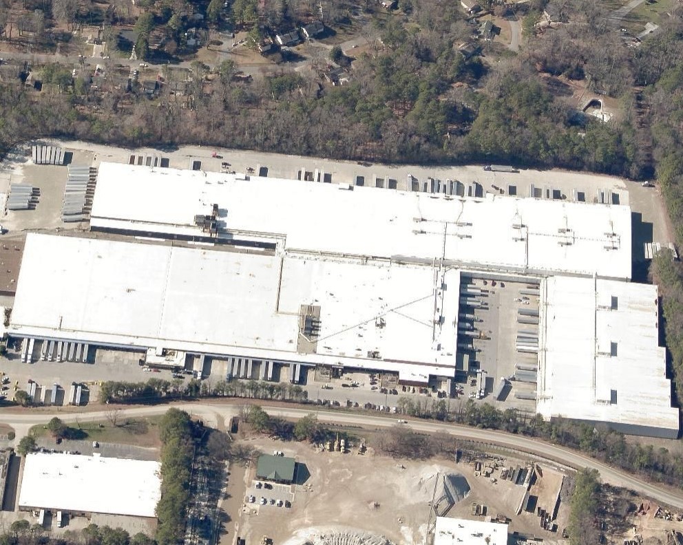 Aerial view of a large warehouse complex with a white roof and multiple loading docks.