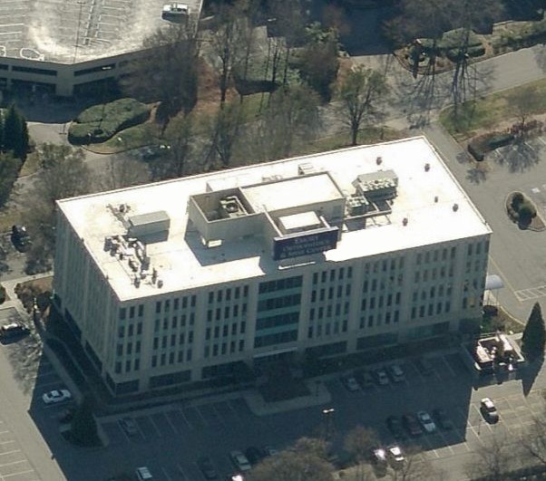 Aerial view of a multi-story office building with a parking lot and a rooftop sign for Emory Orthopaedics & Spine Center.