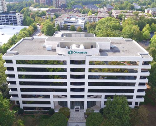 Aerial view of a multi-story office building with a white exterior and horizontal windows, featuring the Oldcastle logo on the roofline.