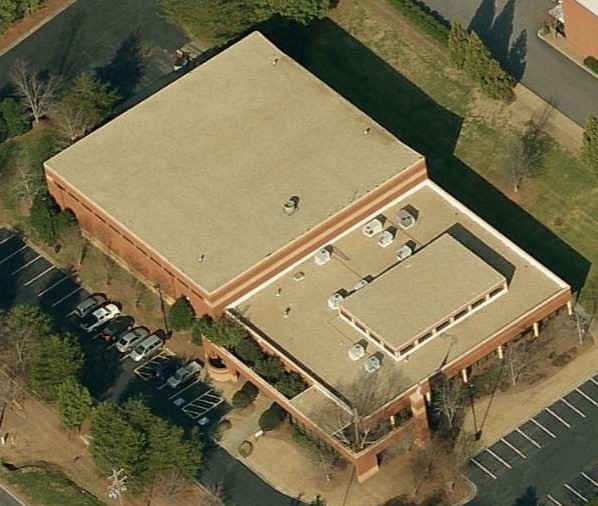 Aerial view of a flat-roofed brick commercial building with adjacent parking lots.