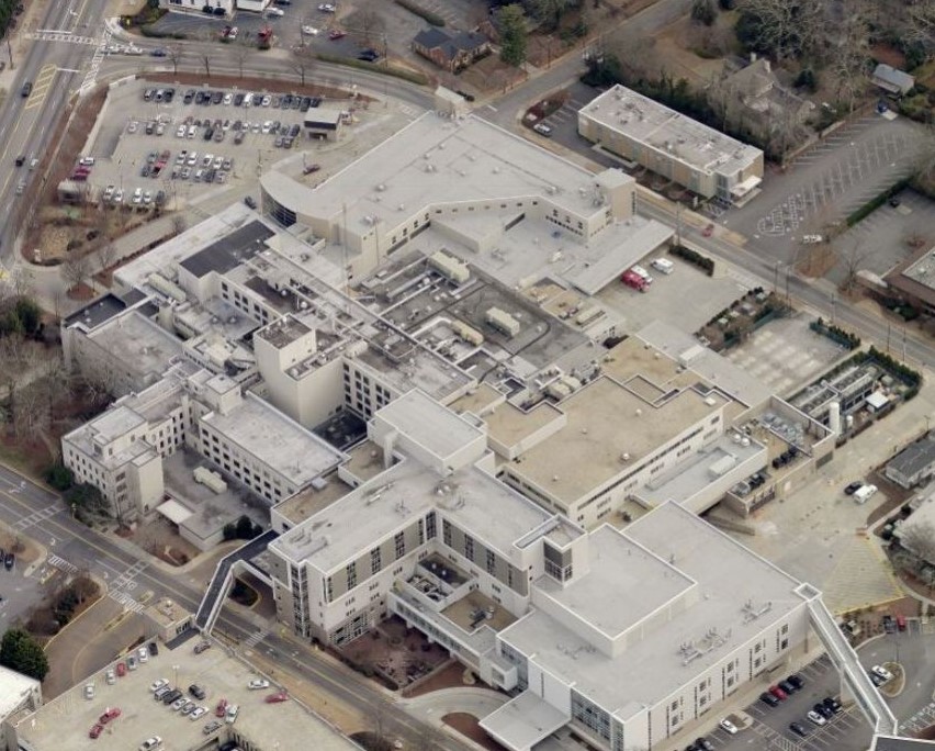 Aerial view of a large hospital complex with connected buildings, parking lots, and surrounding streets.