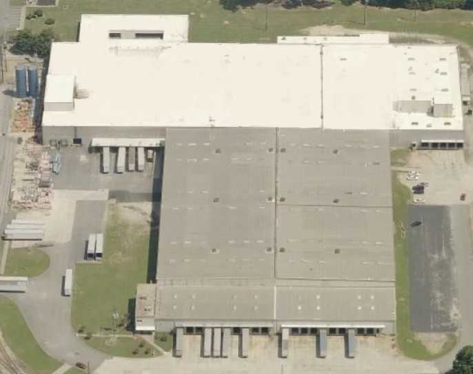 Aerial view of a large warehouse building featuring multiple loading docks and semi-trailers parked alongside.