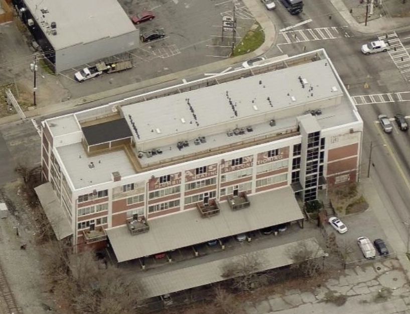 Aerial view of a multi-story brick commercial building with a covered parking area, featuring signage that reads Yates Heating and Air Conditioning.