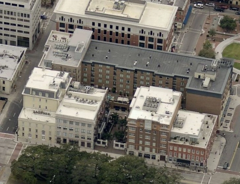 Aerial view of several multi-story brick and light-colored commercial and residential buildings surrounding a central courtyard.
