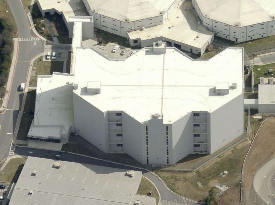 Aerial view of a large, star-shaped prison facility surrounded by paved roads and parking lots.