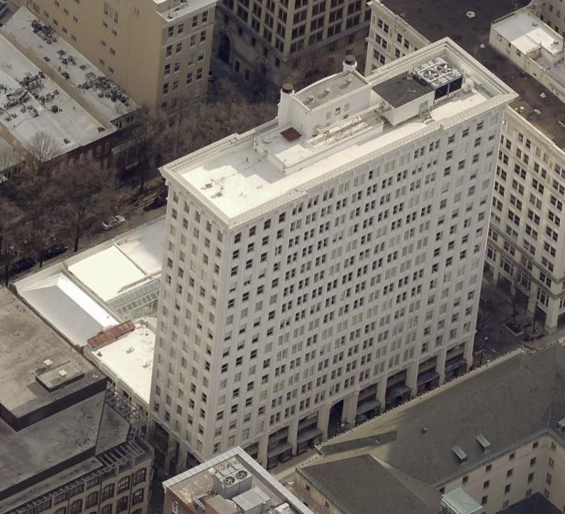 Aerial view of a tall, white rectangular office building in a city center.