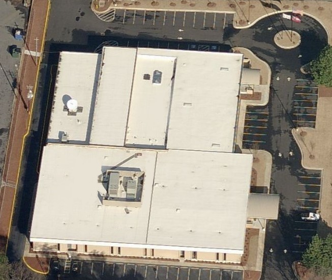 Aerial view of a rectangular commercial building surrounded by a parking lot.