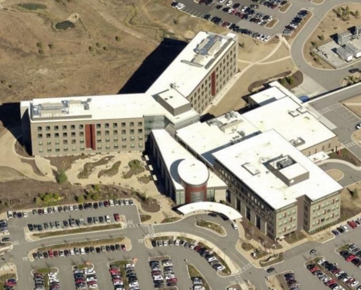 Aerial view of a large multi-wing commercial office building surrounded by parking lots and landscaping.