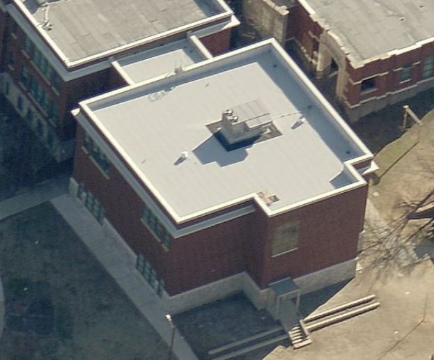 Aerial view of a red brick school building with a flat roof.