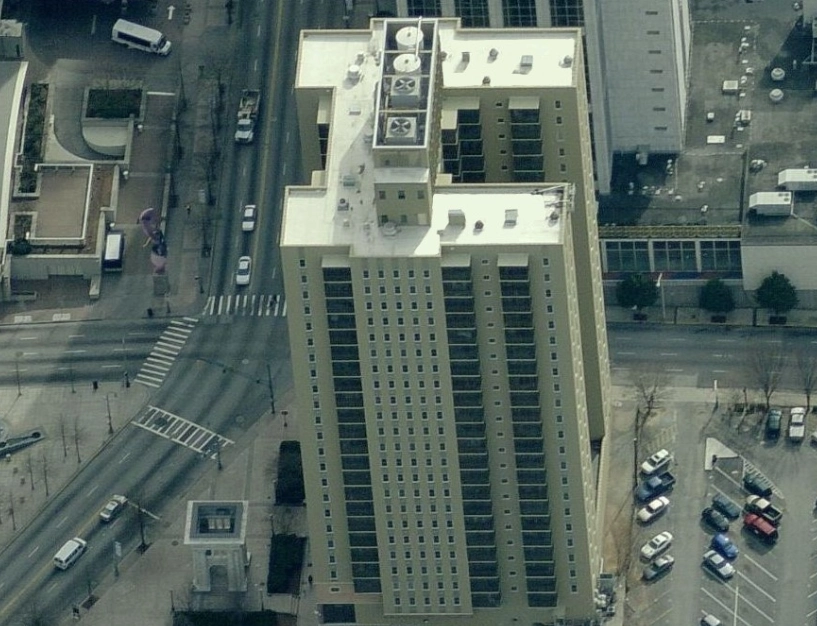 Aerial view of a tall, rectangular apartment building located at a city street intersection.