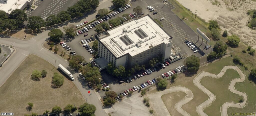 Aerial view of a multi-story hotel surrounded by parking lots and a paved go-kart track.