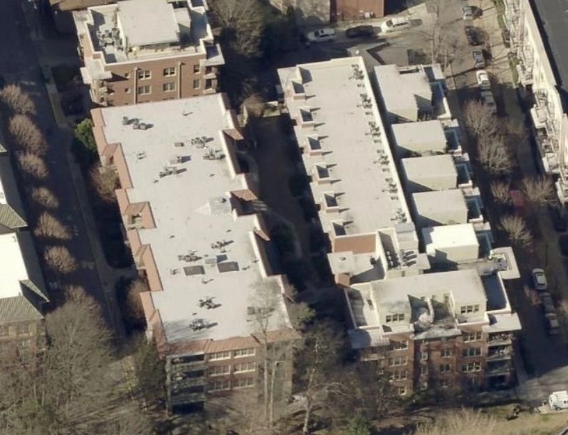 Aerial view of two adjacent residential apartment buildings with flat roofs and rooftop HVAC units.