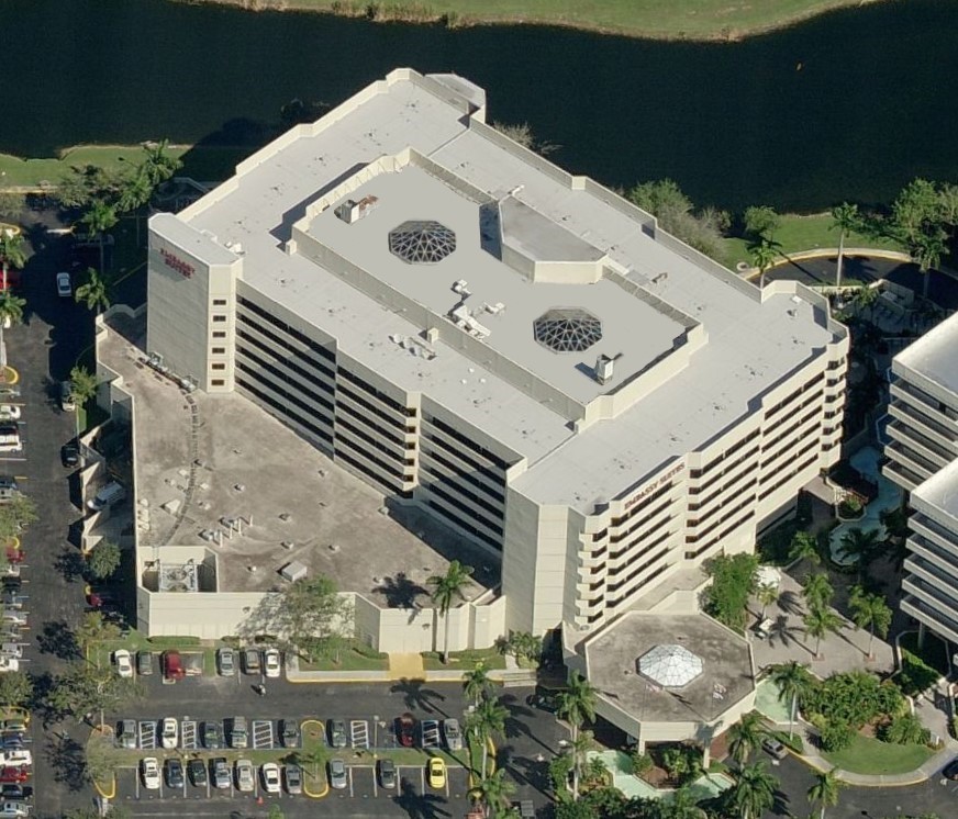 Aerial view of an Embassy Suites hotel with a parking lot and surrounding landscaping.